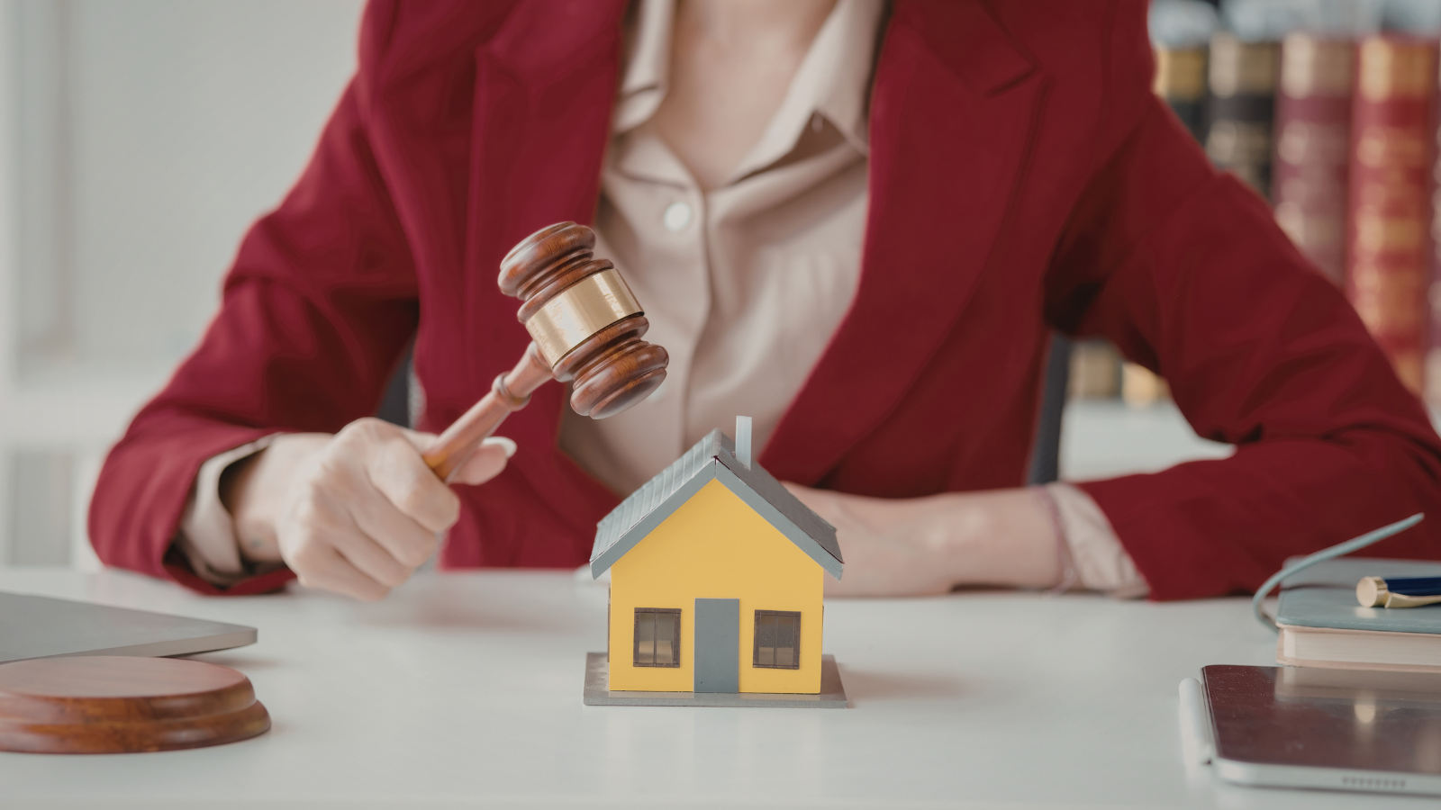 Judge strikes gavel on miniature house symbolizing real estate law